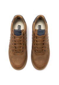 Zapatillas de cuero marrón con puntera perforada, cordones texturizados y lengüeta de tela azul marino. Presentan ojales dorados y una suela de diseño simple.