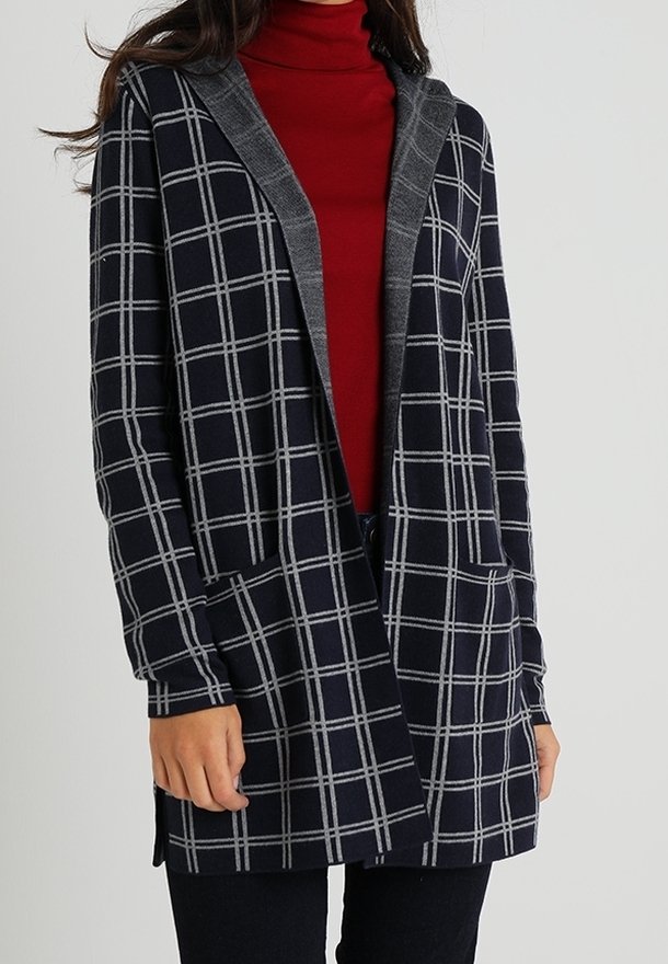 Lång marinblå cardigan med grå rutig mönster, grå huva och framfickor. Bärs över en röd polotröja med långa ärmar och rak skärning.