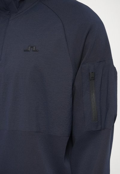 Ναυτικό πουλόβερ με σχέδιο μισής φερμουάρ, υφασμάτινη υφή στο πάνω μέρος, λεία χαμηλότερη περιοχή και τσέπη με φερμουάρ στο μανίκι.