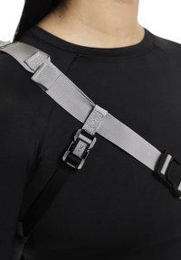 Graue Gurte aus Gurtband mit verstellbarem Schnallendetail, befestigt an einem schwarzen eng anliegenden Kleidungsstück, die ein minimalistisches Design und robustes Material zeigen.