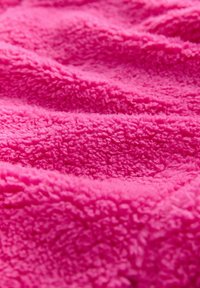  spilvens segums, kas izgatavots no mīkstas, teksturētas auduma, ar pūkainu virsmu viļņveidīgām krokām un mājīgu izskatu.