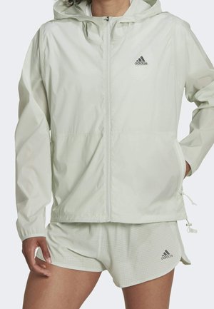 Ljusgrön idrottsjacka med huva, dragkedjestängning och två sidofickor. Har Adidas-loggan i svart. Lättviktig, jämn textur.