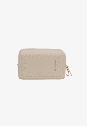 Bolsa de viaje rectangular beige con borde texturizado, cierre de cremallera y logotipo "American Tourister" grabado en el frente.