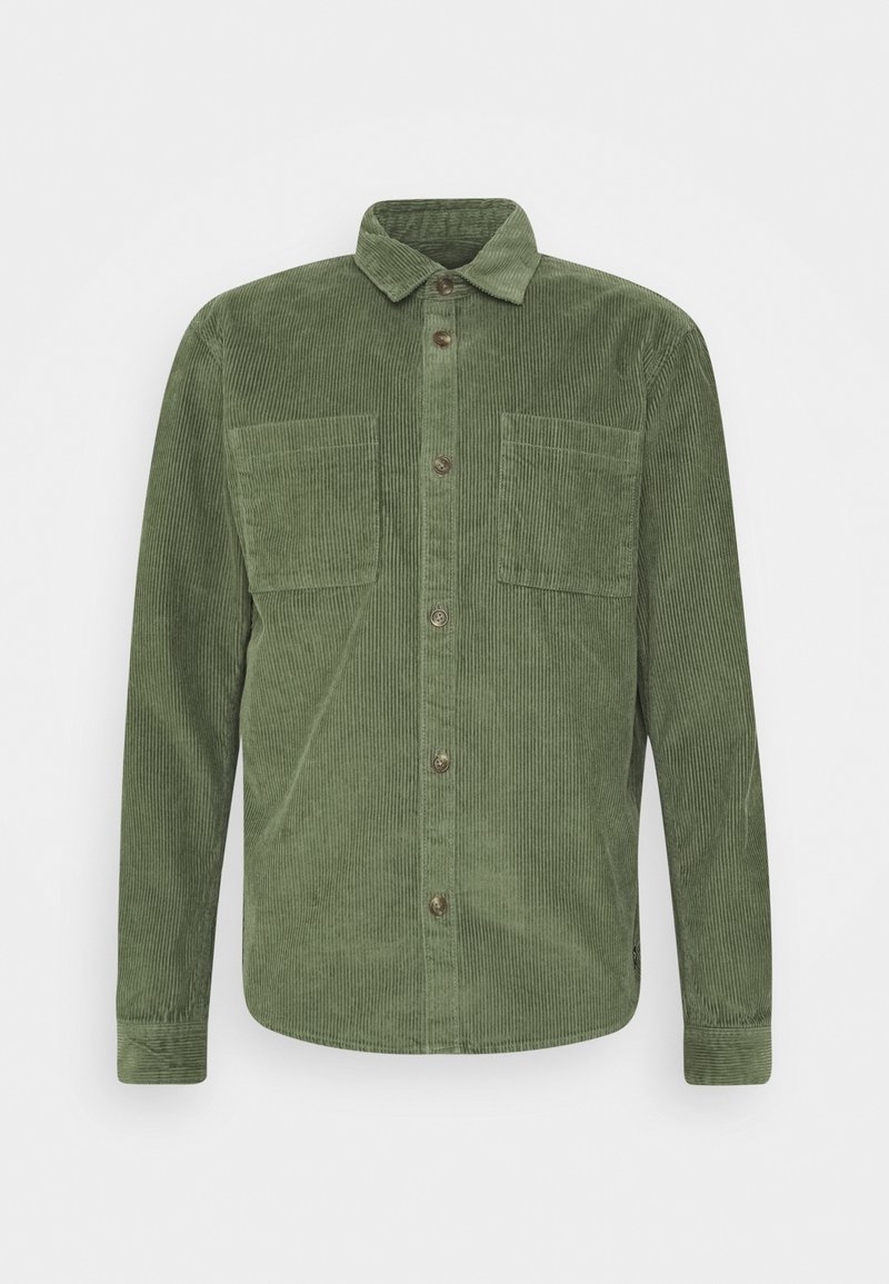 Chemise verte en velours côtelé à manches longues avec boutonnière à l'avant, col, deux poches poitrine et poignets, présentée sur un fond uni.