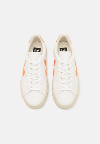 Białe skórzane sneakersy z pomarańczowym akcentem w postaci logo i bocznego panelu, okrągły czubek, płaskie sznurowadła oraz teksturowana podeszwa.