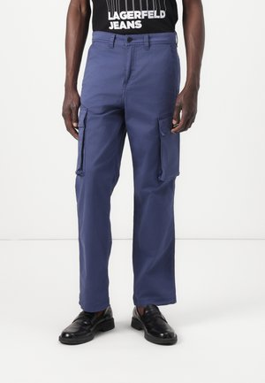 Navy cargo pants featuring a straight cut, multiple side pockets, and a flat waistband. Worn with black loafers and a graphic black t-shirt.
