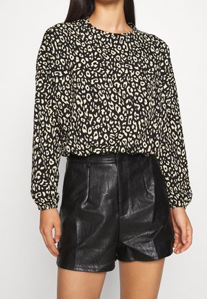 Zwart en ivoor gevlekt blouse met lange mouwen, ronde halslijn en een losse fit, gecombineerd met zwart leren shorts met hoge taille.