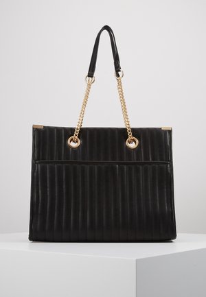 Sac à main rectangulaire noir avec matelassage vertical, anses en chaîne dorée fixées par des œillets ronds dorés, et petits accents dorés aux coins.