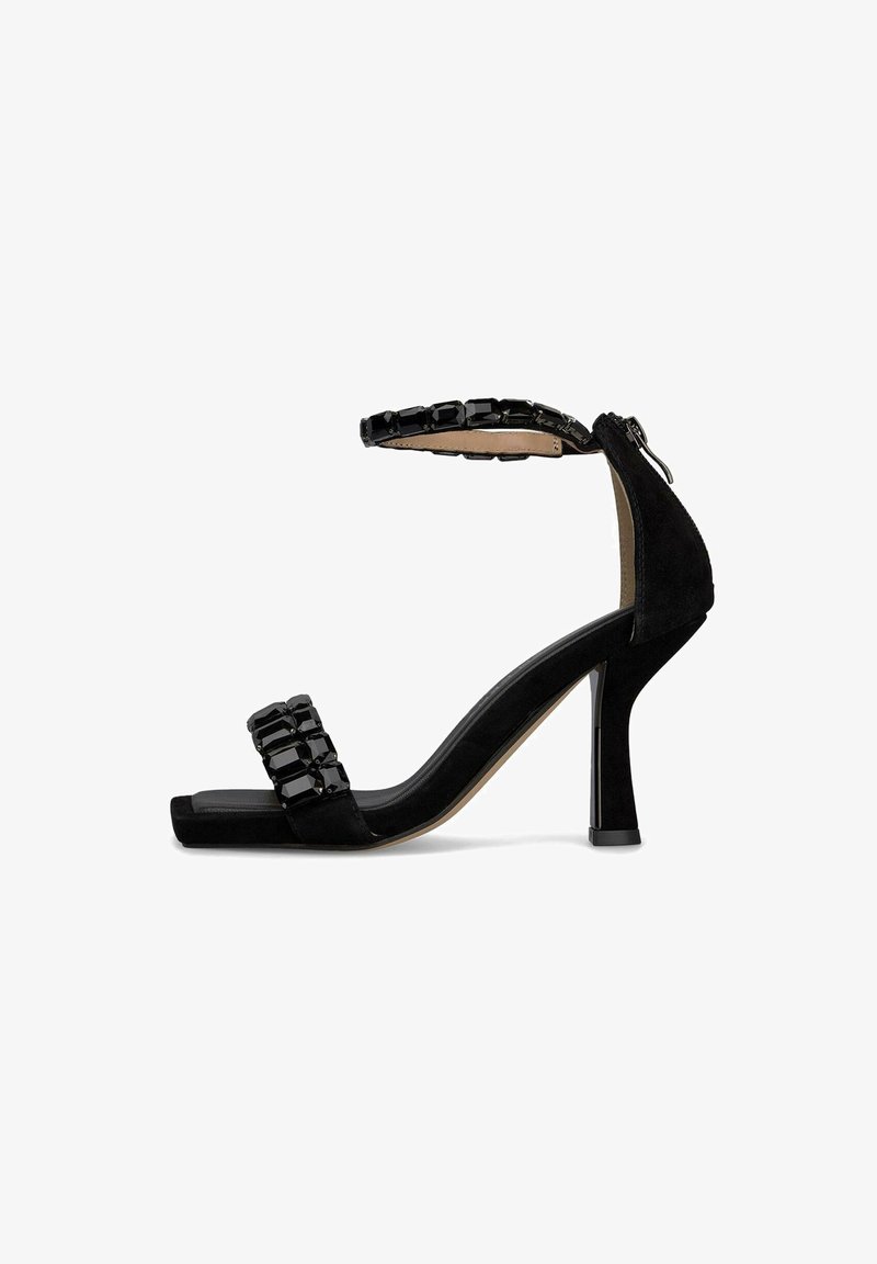 Sandali con tacco alto in suede nero, con una spessa cinturino alla caviglia adornato di perline nere e una punta quadrata. Dettaglio con zip sul retro.