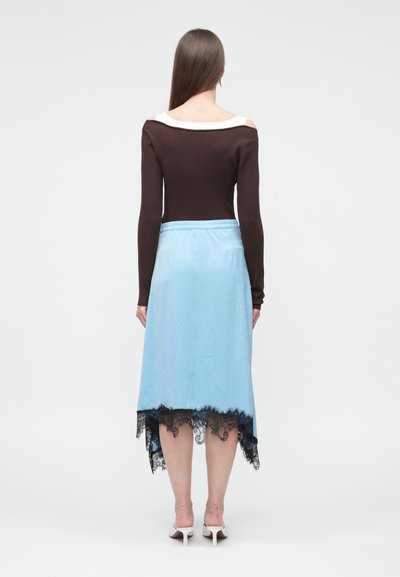 Καφέ ριμπ μπλούζα με μακρύ μανίκι και ανοιχτούς ώμους, συνδυασμένη με ανοιχτό μπλε, σατέν φούστα με μαύρη δαντέλα στο τελείωμα.