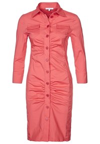 Korallinvärinen napillinen mekko, jossa on neljänneksen pituiset hihat, edessä laskostettu yksityiskohta ja kaksi rintataskua. Sileä kangaspinta.