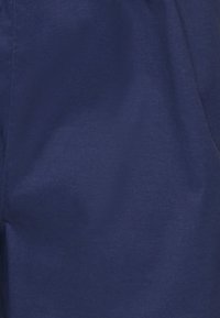 Tkanina w kolorze granatowym o gładkiej teksturze, z subtelnym połyskiem i przeszytymi szwami. Tkanina wydaje się lekka i przewiewna.