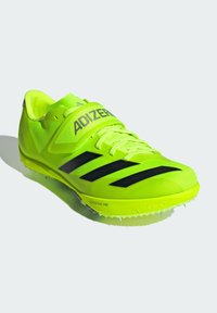 Neon yellow athletic shoe with a textured mesh upper, black three-stripe design, and a lightweight sole featuring white spikes for traction.