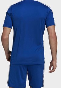 Blå atletisk tröja med korta ärmar, med vita ränder längs axlarna, tillverkad av ett slätt, syntetiskt material.