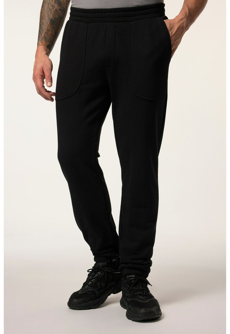 Czarne dresy z żeberkowym pasem, dwoma kieszeniami bocznymi i zwężanymi mankietami, wykonane z miękkiego materiału o gładkiej fakturze.