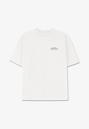 T-shirt bianco in cotone con una vestibilità rilassata. Presenta un collo rotondo e maniche corte. Stampa "Cozy Club" in grigio chiaro sul lato sinistro del petto.