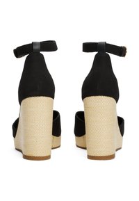 Talons compensés noirs en toile avec une bride à la cheville, dotés d'une base tissée beige et d'une finition texturée. Les semelles sont brun.