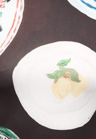 Λευκό πιάτο με ένα κίτρινο φρούτο και πράσινα φύλλα ζωγραφισμένα σε σκούρο καφέ υφασμάτινο φόντο με υφή.