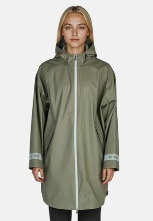 Woman wearing a long olive-green raincoat with a hood, front zipper, side pockets, and reflective cuffs labeled "NO.1 COMO."