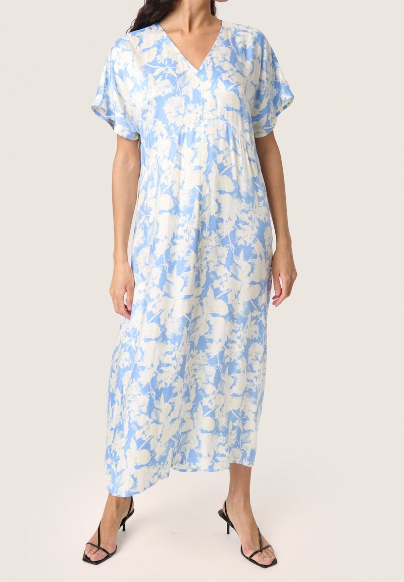 Lång, löst sittande klänning i ljusblått med vita blommönster. V-ringning, korta ärmar och mjukt tyg med en slät yta.