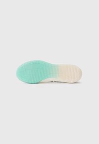 Sko såle med gradientdesign som går fra teal til gjennomsiktig beige, med en teksturert overflate og mønstrede spor for grep.