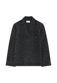 Chemise noire à manches longues avec un col en V, ornée de petits points blancs dispersés. Fabriquée en tissu doux, elle possède un col et des fentes sur les côtés.