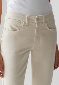 Beige, hooggewrongen jeans met een gladde textuur, met voorzakken, een sluiting met een voorste knoop en subtiele stikseldetails.