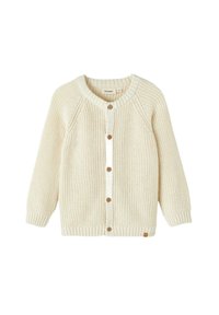 Kreminė megzta kardiganas su apvaliu kaklu, raglanų rankovėmis, mediniais mygtukais ir gumuluotais rankogaliais. Paprasta tekstūra ir švarus dizainas.