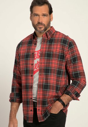 Rood en zwart geruite blouse met lange mouwen en een neklap, gecombineerd met een grijs T-shirt met rode tekst, gedragen met zwarte broek.