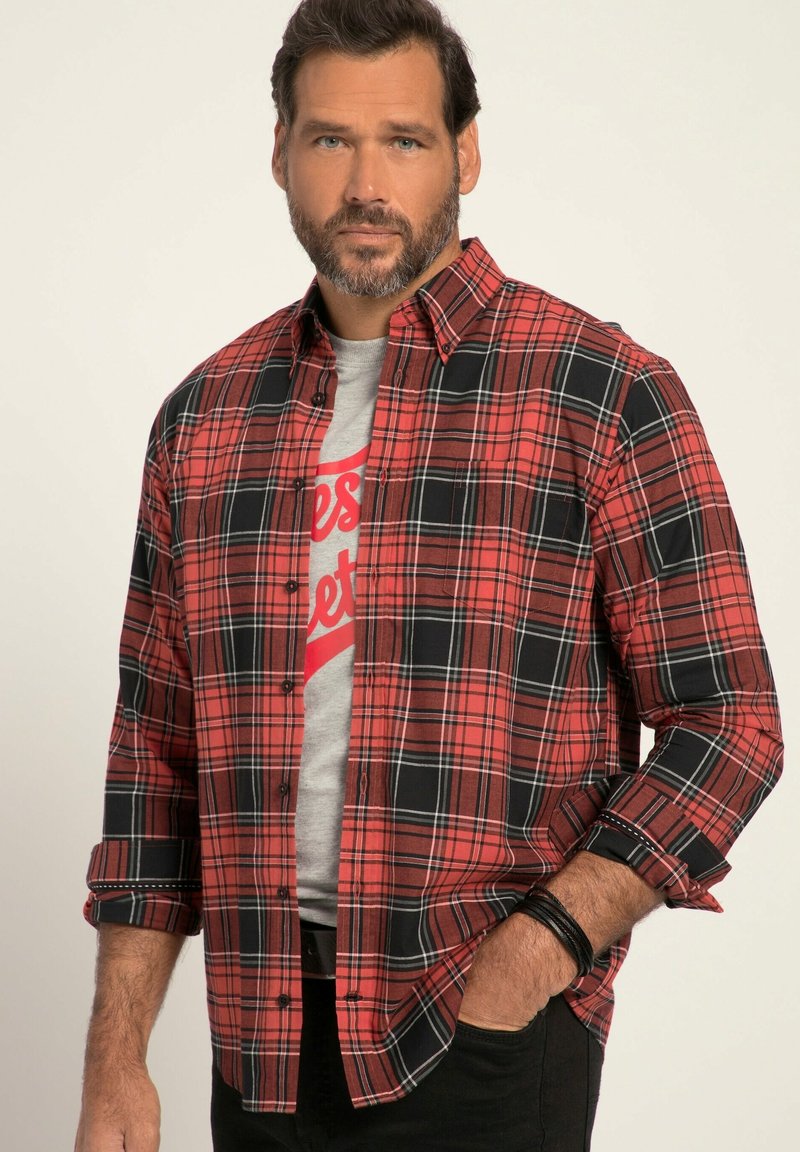 Rot-schwarz karierte Langarmbluse mit Button-Down-Kragen, kombiniert mit einem grauen T-Shirt mit rotem Text, getragen zu schwarzen Hosen.