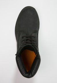 Bottine en cuir noir avec un bout arrondi, un col rembourré et une doublure intérieure orange. Elle dispose de lacets noirs et de détails de couture subtils.
