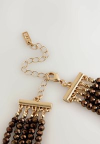 Goldfarbene Metallkette mit einem Karabinerhaken, die mit Strängen von dunkelbraunen, facettierten Perlen und zwei horizontalen Stangen oben versehen ist.