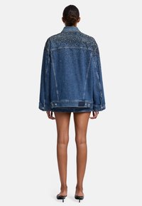 Giacca di jeans con vestibilità rilassata, colore blu scuro, impreziosita da strass sulle spalle e sulla parte superiore della schiena, dotata di tasche laterali.