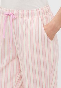 Ljusrosa randiga byxor med vit bas, mjukt bomullsmaterial, elastisk midja med en rosa snörning och sidofickor.