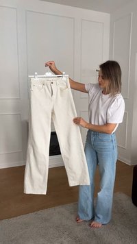 Jeans bianchi a gamba larga realizzati in cotone, con un design semplice, cuciture visibili e due tasche posteriori. Appesi a un gancio in plastica.