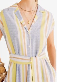 Vestito camicia a bottoni in blu, giallo e pesco a righe. Maniche corte, colletto e cintura in vita. Realizzato in tessuto leggero.