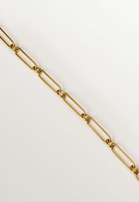 Cadena de metal dorado con eslabones ovalados alargados, superficie lisa y un acabado uniforme, descansando plana sobre un fondo neutro.