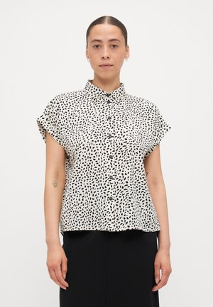 Short-sleeved, button-up blouse in cream with a black abstract pattern. Features a collar and a loose fit, made from a lightweight fabric.