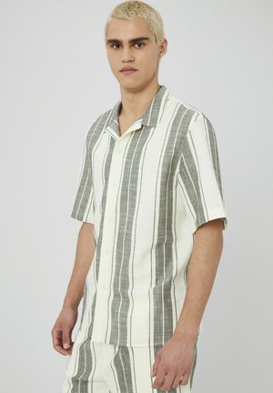 Chemise à manches courtes avec boutons, blanche rayée de vert vertical, dotée d'un col à encoches et d'un tissu texturé.
