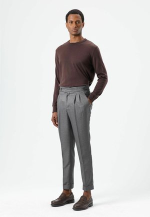 Brown long-sleeve knit sweater paired with high-waisted gray tailored trousers featuring pleats and side buttons. Brown loafers complete the look.