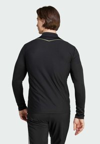 Zwart sportief longsleeve top van textuurstof, met een subtiele groene accent langs de kraag en een aansluitende pasvorm.