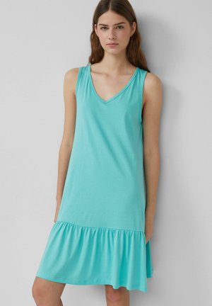Ein türkisfarbenes ärmelloses Kleid mit V-Ausschnitt. Der Saum hat eine Rüschendetail und ist aus leichtem, weichem Stoff gefertigt. Einfaches Design.