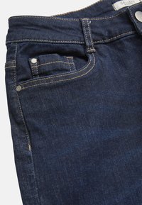 Tummansiniset denim-farkut, joissa on kontrastiväriset tikkaukset, klassinen viiden taskun muotoilu sekä hopeiset napit ja niitit.