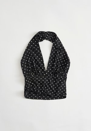 Black halter neck crop top with white polka dots, deep V neckline, and ruched detailing on a light background.