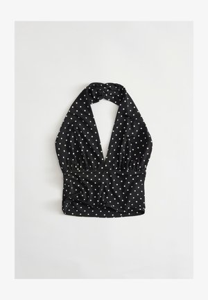 Black halter neck crop top with white polka dots, deep V neckline, and ruched detailing on a light background.
