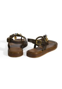 Braune Ledersandalen mit flacher Sohle, dekorativen Perlen und goldfarbener Hardware. Enthält einen verstellbaren Riemen für einen sicheren Sitz.