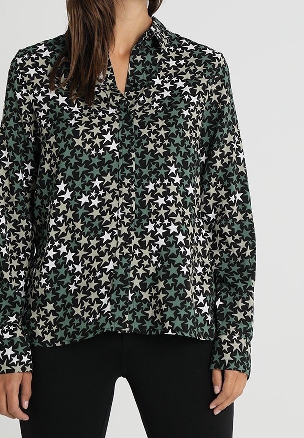 Camisa de manga larga con botones en tela de color verde oscuro, con un patrón de estrellas en tonos blancos, beige y verdes más claros. Diseño de cuello clásico.
