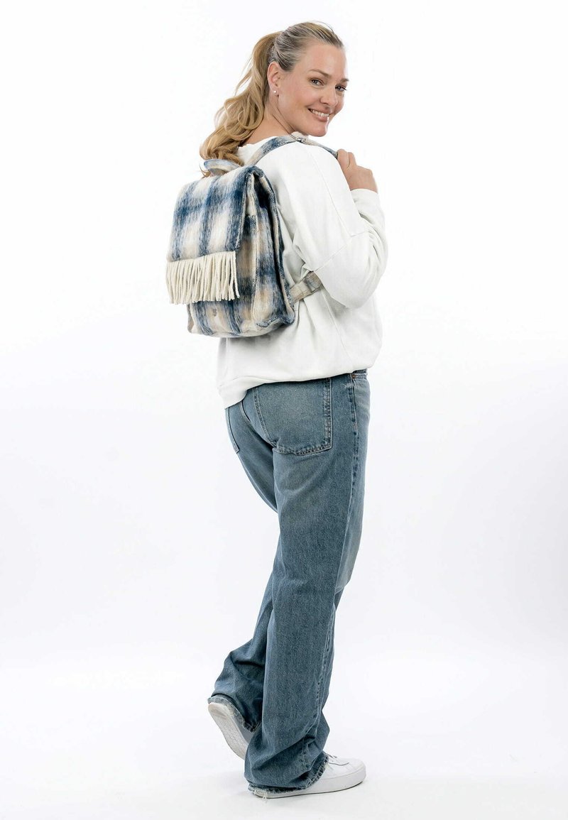 Rucksack mit einem blau-weißen Batikmuster, ausgestattet mit einer strukturierten Oberfläche und cremefarbenen Fransenakzenten. Verstellbare Träger und rechteckige Form.