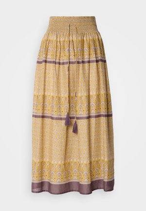 Gul maxi skjørt med smocket midje, blomster- og geometriske mønstre i hvitt og lilla, med to lilla dusker i midjen.