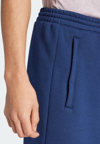 Námornické modré tepláky s elastickým pasem, boční kapsou a měkkou texturou. Tkanina vypadá odolně a lehce.